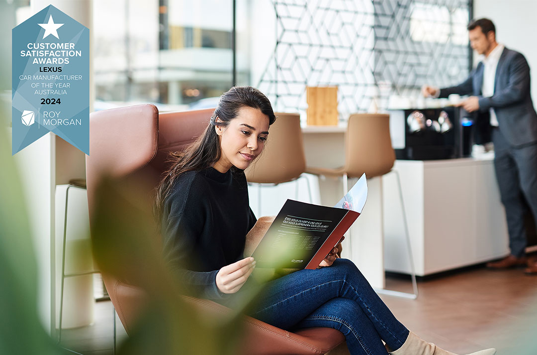 Woman in a lounge reading brochure, Lexus 'Car Manufacturer of the Year 2024' award logo in corner